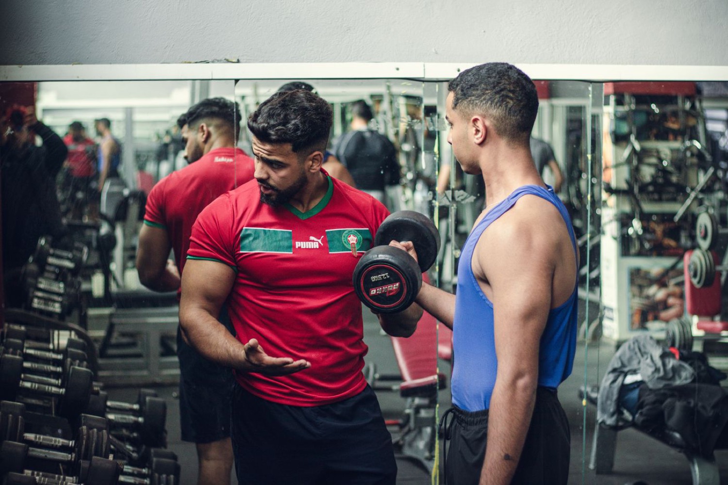 A coach talking a member through a dumbbell exercise
