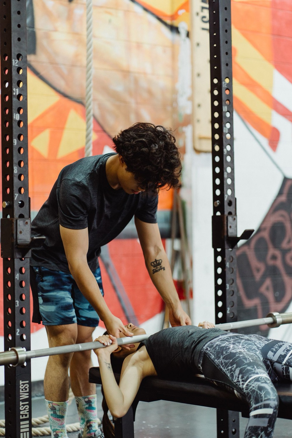 A trainer spotting a client through a bench press set